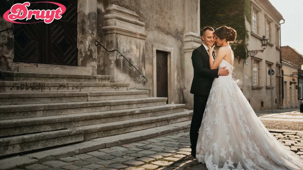 A romantic couple standing in front of an old stone building, sharing an intimate moment on their wedding day. Can you get invited to a wedding? It often depends on how close you are to the couple and the size of the wedding.